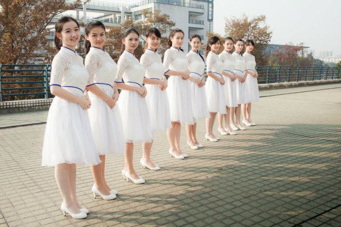 点击大图看下一张：近日，浙江大学礼仪队一张照片在微博上转得很火，10位女生穿着白色镶蓝边的礼服，站成一排，双手叠放在身前，笑得很灿烂.，照片中的美女清一色的马尾辫尤其抢眼。
