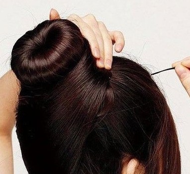 点击大图看下一张:现在我们可以处理下面部分的头发了。将左边的头发向着头顶的右上方梳理整齐,然后将其缠绕在头顶位置发髻的底部,绕圈处理,然后用小发夹将发丝固定好。