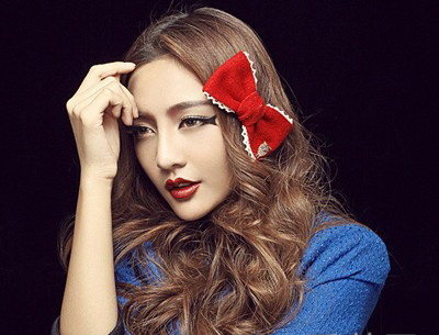 点击大图看下一张:中分的大波浪长卷发,暖色系的发色上面一抹红色的蝴蝶结让发型瞬间惊艳,眼睛处的鱼骨眼线画法同样吸引人。