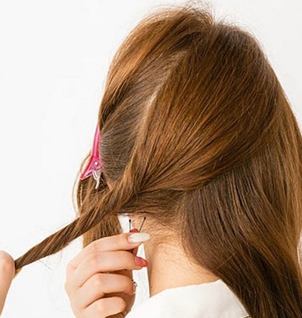 点击大图看下一张：步骤一：首先将头发分成三个局域，将前面的一束头发用夹子夹好，中间的发束扭转后再用发夹固定。