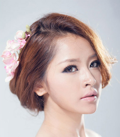 点击大图看下一张：最新韩式新娘发型三：棕色头发蓬松盘起，再配上与唇色相呼应的粉色花朵，瞬间变身高雅新娘。