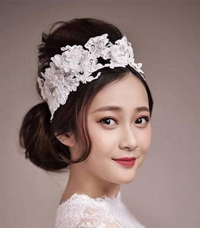 点击大图看下一张：最新韩式新娘发型五：将头发分成两大部分分别盘成发髻，高耸的发包与侧边发髻，彰显个性，且拉高新娘身高，搭配上洁白发带，营造出婚礼气氛。