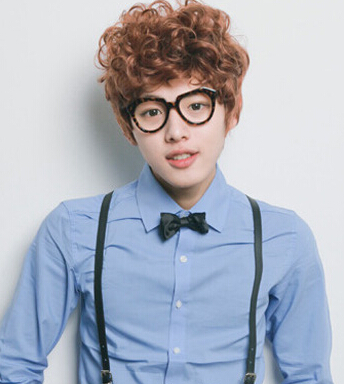 点击大图看下一张：这款韩国男生短卷发发型，个性的卷发加上时尚的栗子色染发色，搭配一款圆框眼镜，斯文中又不失可爱。