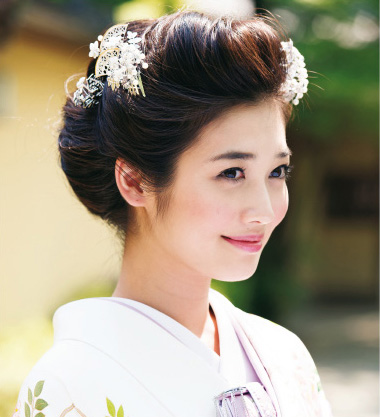 点击大图看下一张：日本女人和服发型图片一：将刘海扭转式往头顶固定，在发髻间别上小扇子和小花发饰，显得更加温婉大方。