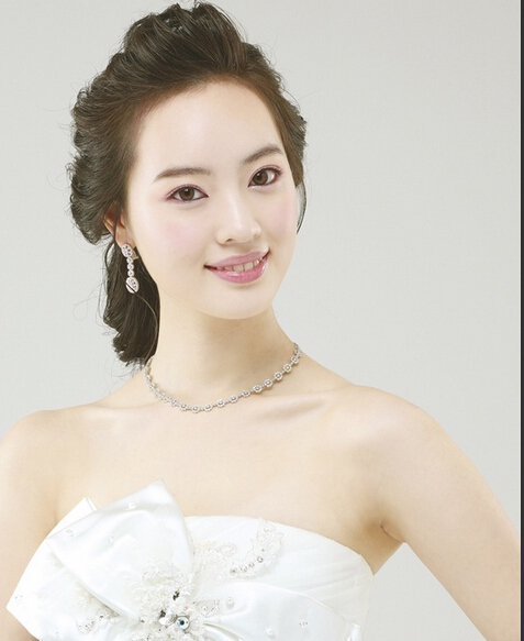 点击大图看下一张：这款唯美的韩式新娘盘发发型，刘海全部侧梳在脑后，头顶的发丝打造隆起的造型，更能凸出新娘精致的五官。