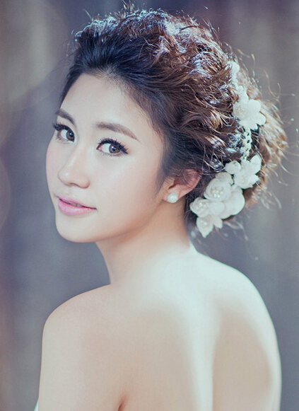 点击大图看下一张：精致而甜美的妆容，配上一头蓬松而凌乱的韩式新娘盘发造型，少许的个性时尚美，花朵发饰的点缀后，更是呈现浪漫气息。