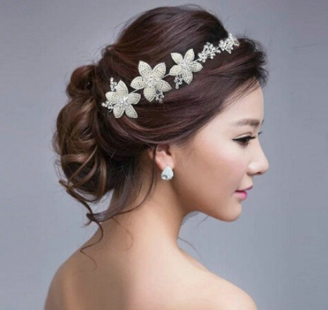 点击大图看下一张：韩式新娘盘发发型一：稍带蓬松的韩式新娘盘发，漂亮的花朵发箍，点缀出唯美春天气息，整个造型出来的感觉是淑女又唯美，稍带蓬松的盘发非常浪漫哦！
