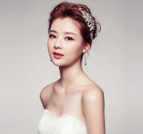 点击大图看下一张：韩式新娘盘发发型三：刘海打造一定的高耸感，气质和优雅加倍哦，随性自然的发丝透出不规则感，一种独特的凌乱美在新娘的头上产生了，配合漂亮的白色发箍，真的太美了。