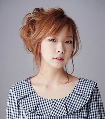 点击大图看下一张：韩式刘海发型二：棕色卷发随意的绾在脑后，斜刘海优雅随性，两鬓卷曲的刘海增添丝丝女人味，甜美迷人。