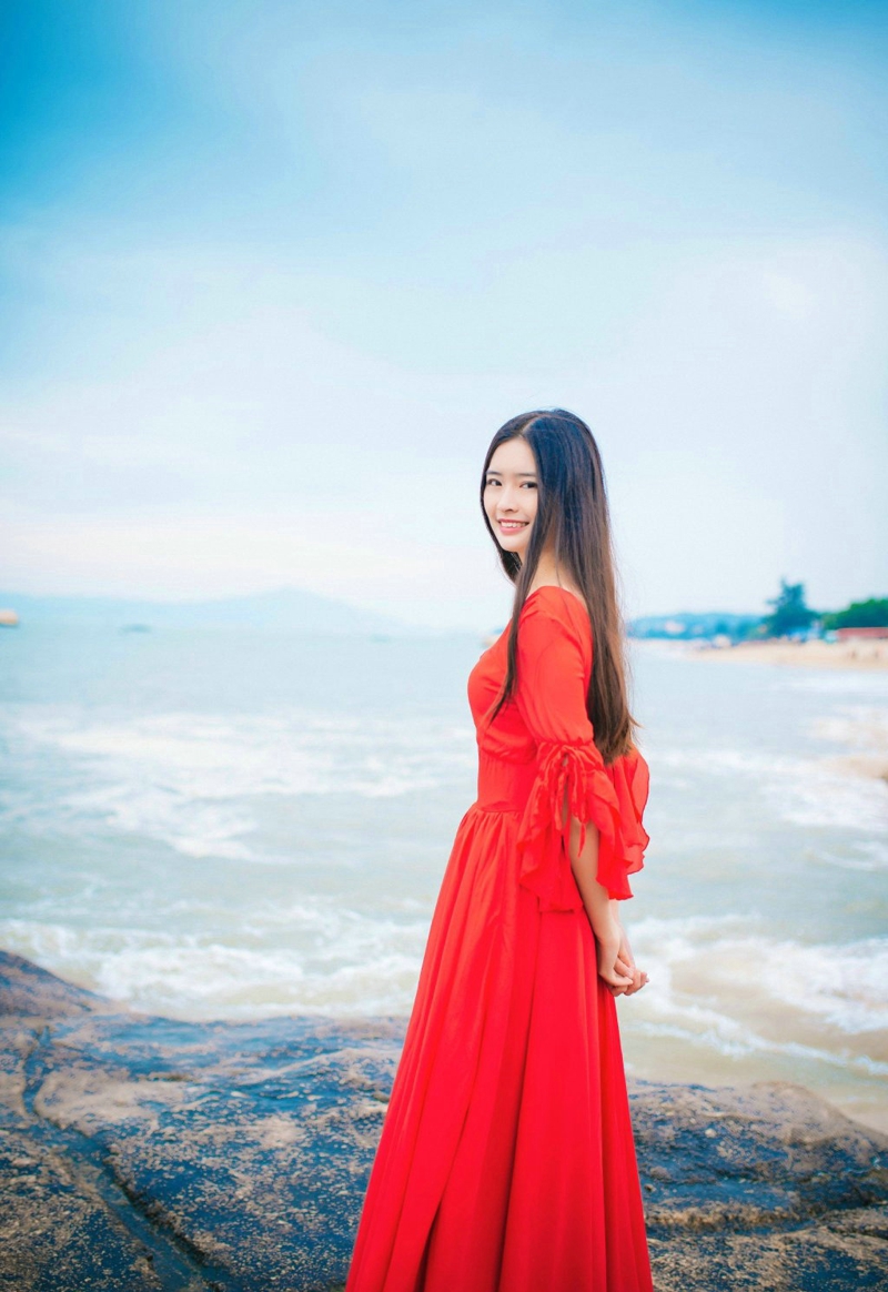 点击大图看下一张：海边晴空下的红裙长发女神笑脸迷人