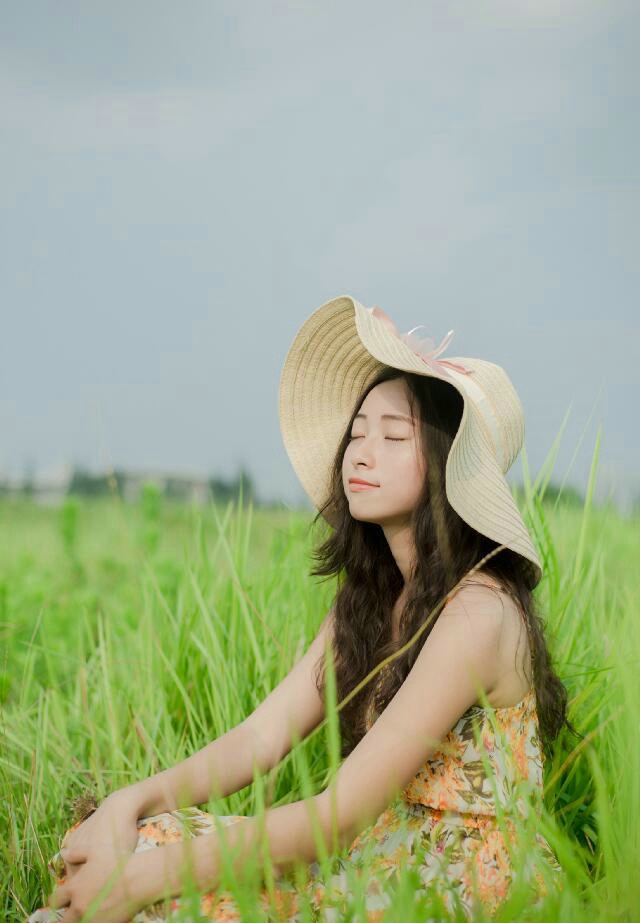 点击大图看下一张：草地上的长裙草帽美女明媚笑容
