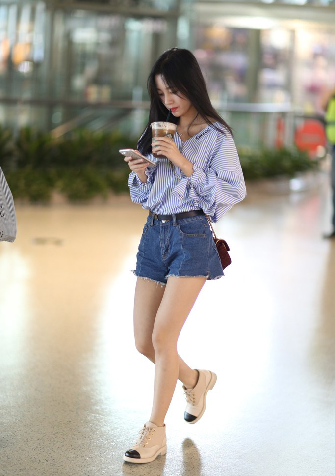 点击大图看下一张：鞠婧祎手端咖啡现身机场晒美腿狂玩手机