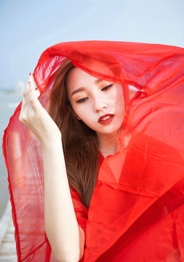 点击大图看下一张：鲜艳红裙美模海边被风吹长发飘逸手捧花令人怜爱