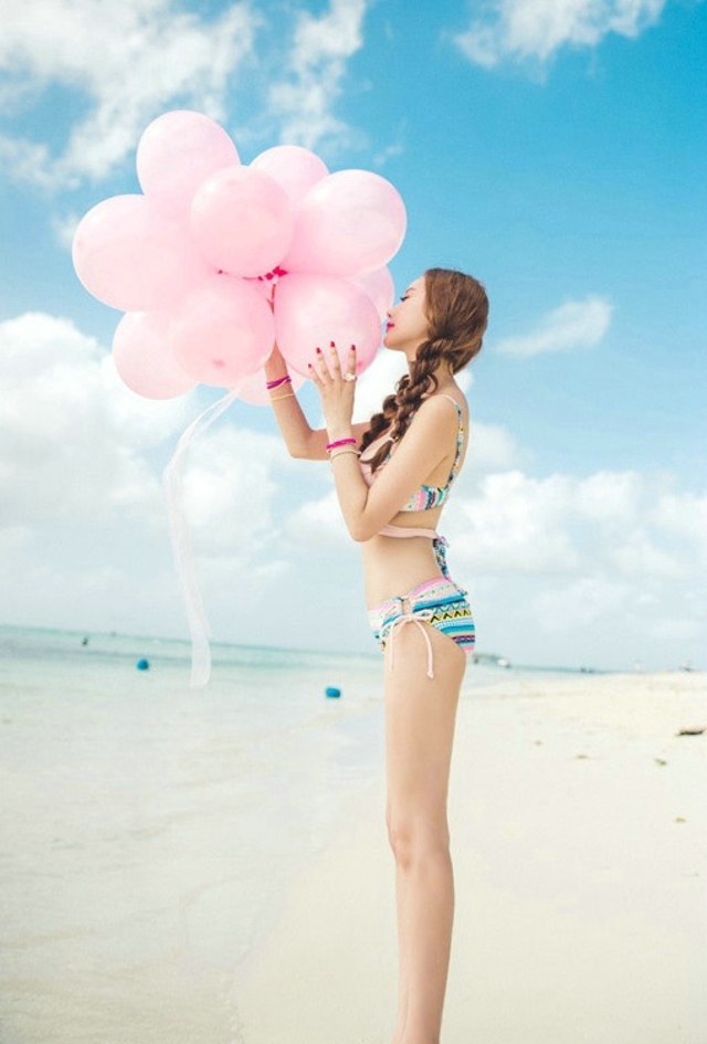 点击大图看下一张：美腿嫩模粉色比基尼海边写真手拿气球满脸享受