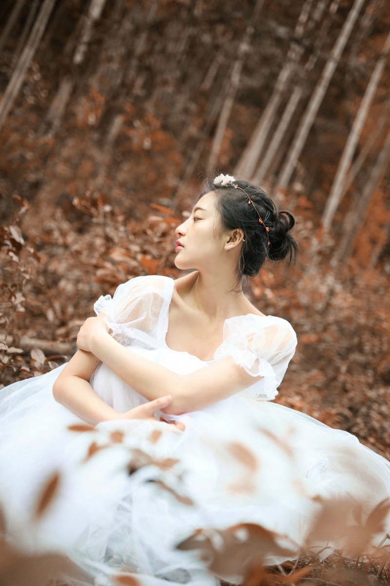 点击大图看下一张：深秋落叶堆中的白纱裙气质盘发美女