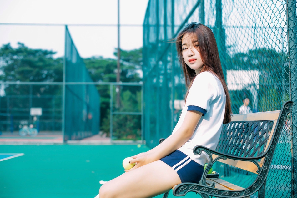点击大图看下一张：网球场上的运动女孩长发飘逸盘腿而坐喝水