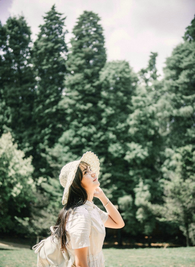 点击大图看下一张：森林公园内的白裙草帽背包少女清爽怡人