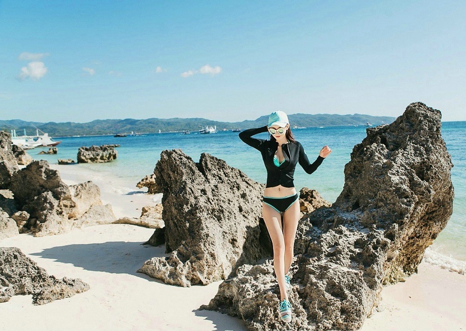 点击大图看下一张：海边礁石上的运动装美女拉链下滑露酥胸