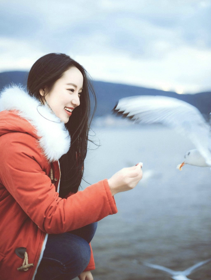 点击大图看下一张：寒冷冬季海边与海鸥玩耍的长发飘飘美女温馨写真