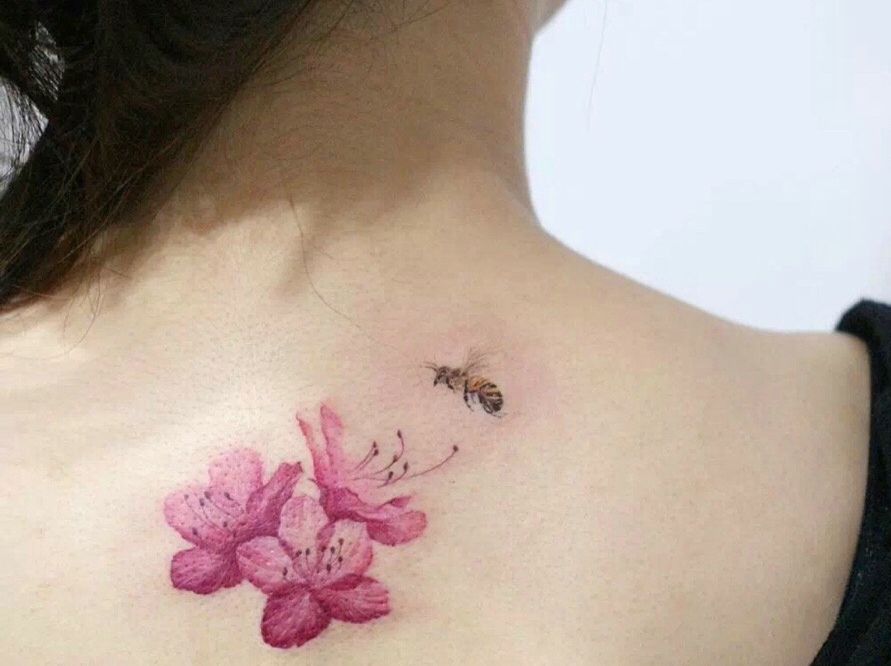 点击大图看下一张：女生背部一只蜜蜂和花卉纹身图案