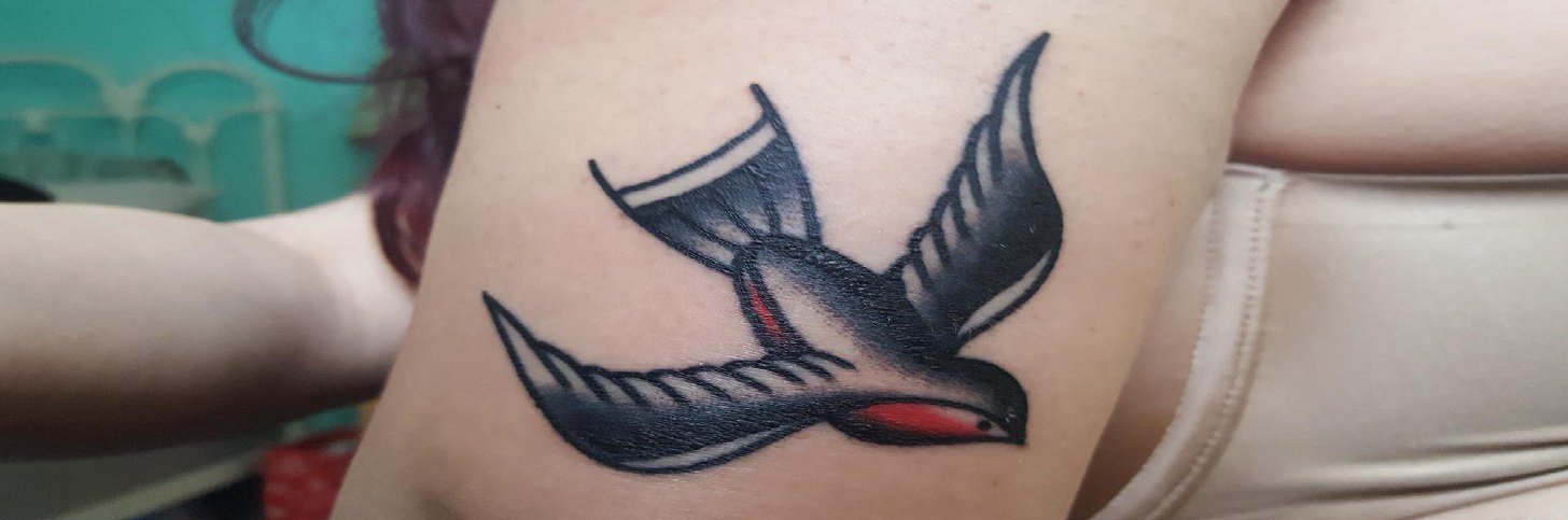 点击大图看下一张：女性左手大臂上漂亮的传统风格燕子纹身图片