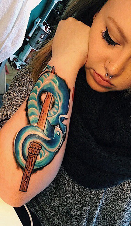 点击大图看下一张：女子手臂上的木剑和蓝色蛇纹身图片