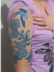 女性手臂上漂亮时尚的花蕊燕子刺青