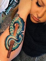 女子手臂上的木剑和蓝色蛇纹身图片