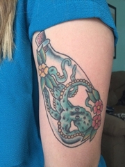 女性左手臂上漂流瓶里的绿色章鱼和花纹身图片