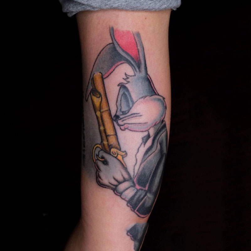 点击大图看下一张：手臂上持枪的帅气兔八哥卡通纹身图案