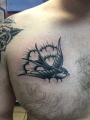 男性胸部上的黑色飞翔中的燕子纹身图片