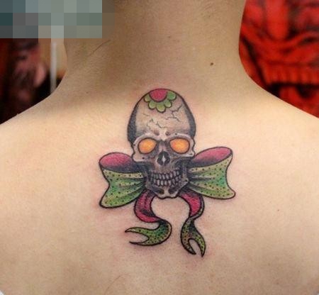 点击大图看下一张：女孩子背部小巧的骷髅与蝴蝶结纹身图案