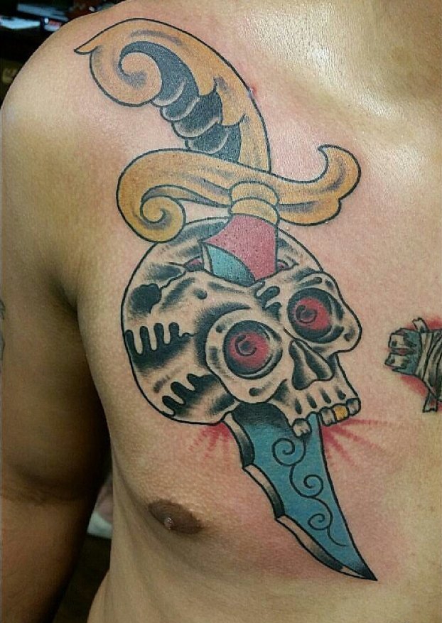 点击大图看下一张：男子胸部上的大头骨和匕首纹身图片