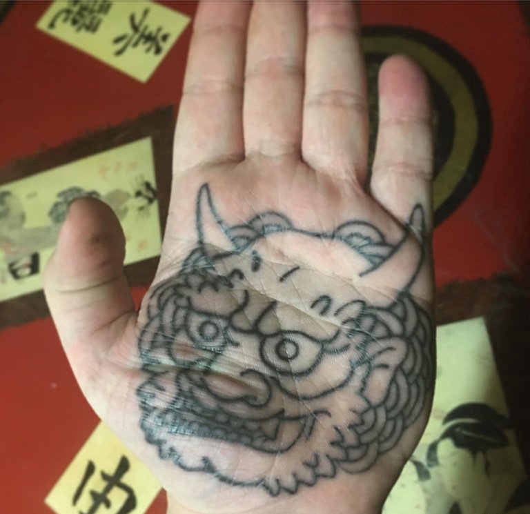点击大图看下一张：手掌上的带角的唐狮怪兽纹身