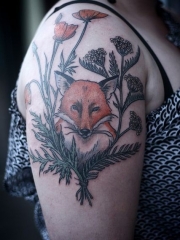 女性手臂上花丛中的狐狸纹身图案