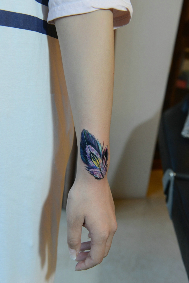 点击大图看下一张：女生手腕上个性十足的彩色羽毛纹身图案