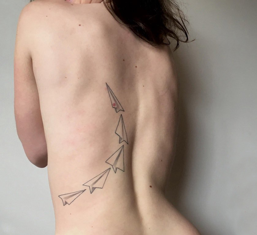 点击大图看下一张：女生后背上黑色点刺几何简单线条纸飞机纹身图片