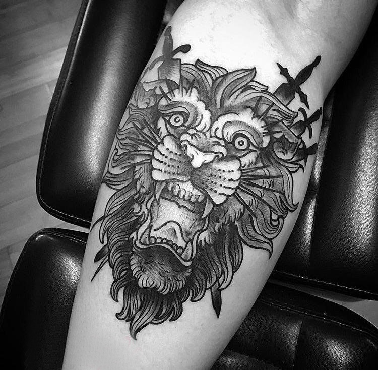 点击大图看下一张：狮子头纹身图片小腿上黑色双剑刺入狮子头纹身图片