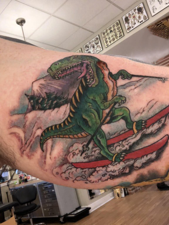 点击大图看下一张：恐龙纹身图案 男生大臂上滑雪的恐龙纹身图片
