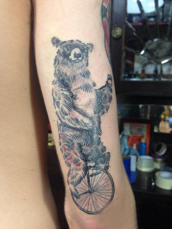 点击大图看下一张：熊纹身 男生手臂上骑自行车的狗熊纹身图片