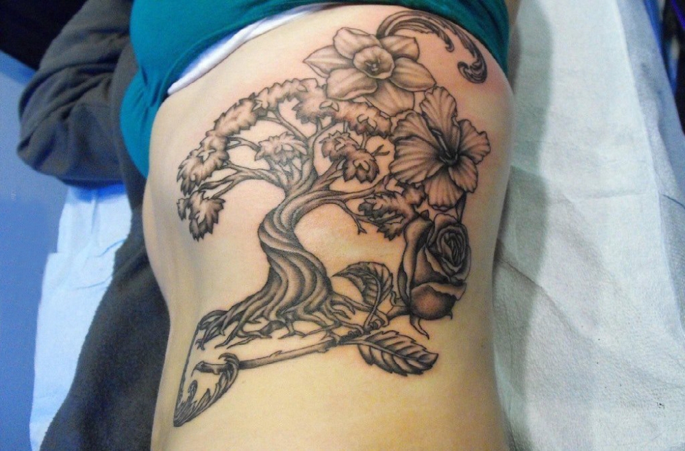 点击大图看下一张：植物纹身  女生侧腰上黑灰的植物纹身图片