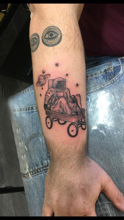 点击大图看下一张：宇航员纹身图案 男生手臂上坐推推车里的宇航员纹身图片