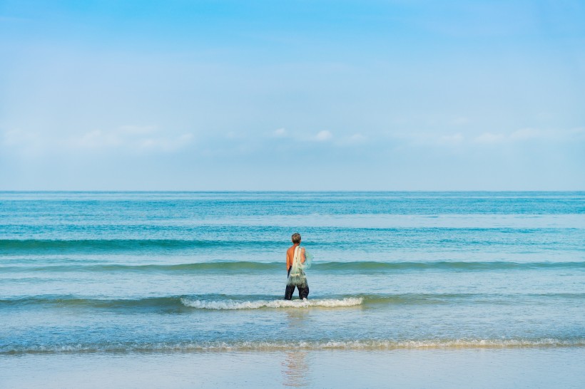点击大图看下一张：站在海边拍照的人图片