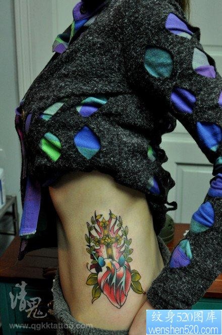 点击大图看下一张：美女侧腰精美潮流的十字架心脏纹身图片