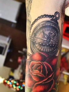 指南针和玫瑰花一起的手臂纹身
