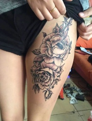 女生大腿落着两朵黑白花朵纹身