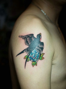 大臂一只小燕子采花的个性纹身图片