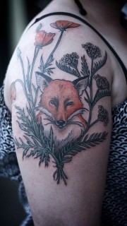 女性手臂上花丛中的狐狸纹身