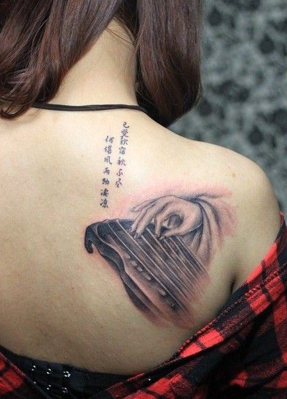 点击大图看下一张：女生背上女子弹琴个性纹身