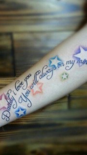 小臂上彩色星星和英文组合的刺青